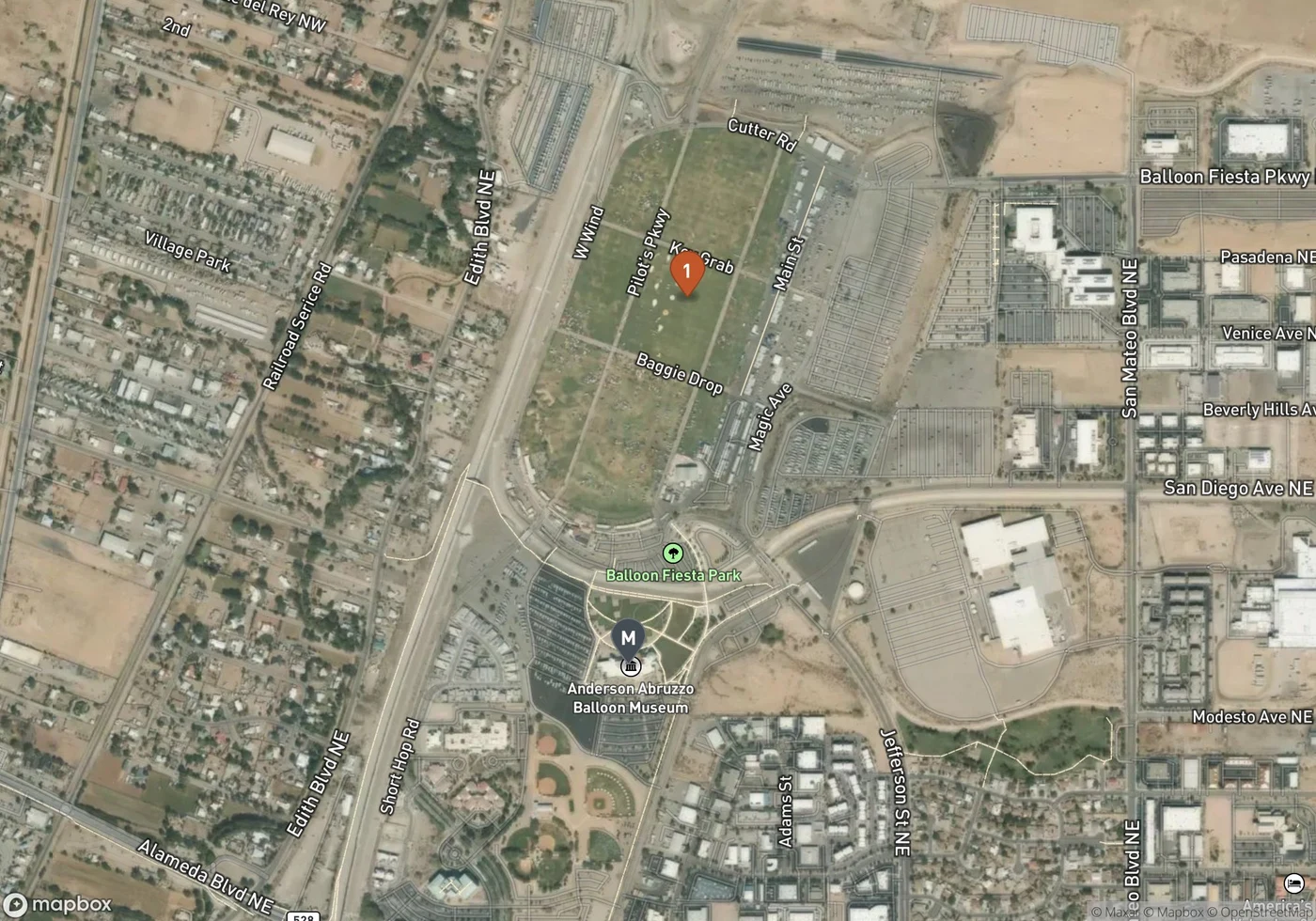 Satellite map of Balloon Fiesta Park showing the long rectangular grass launch field marked 1, with its grid of named lanes including Main Street, Pilot's Parkway, Magic Avenue and Baggie Drop, bordered by Edith Boulevard to the west and parking lots to the east, and the Anderson Abruzzo Balloon Museum marked M at the southern end of the park near Alameda Boulevard.