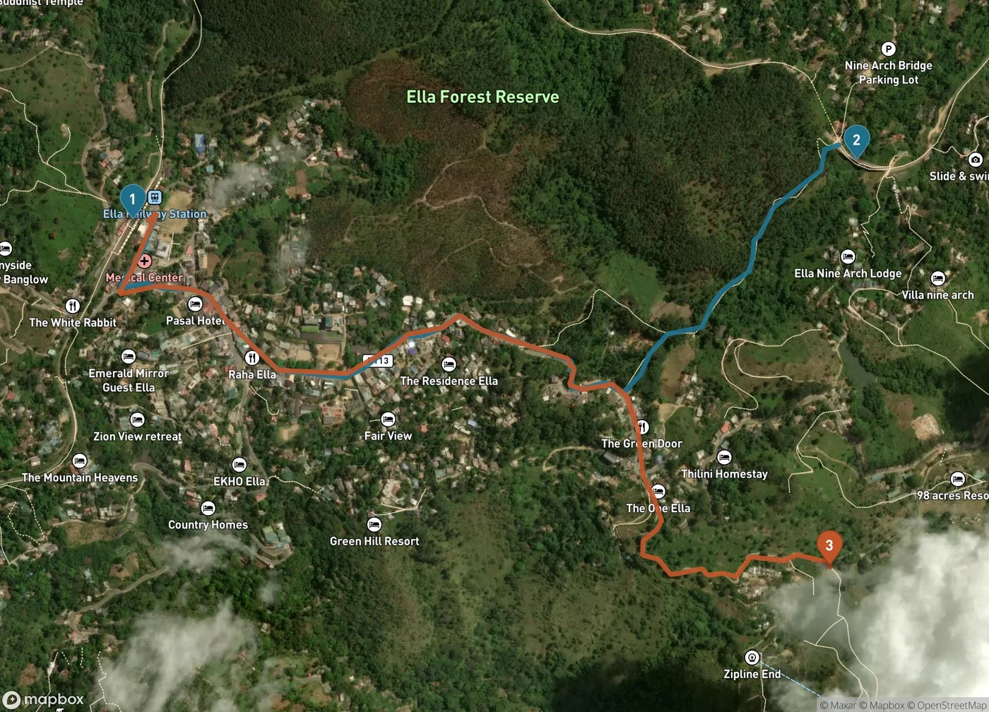 Satellite map of Ella, Sri Lanka. Ella Railway Station is marked 1 at the upper left. A blue walking route runs east through the town and up to the Nine Arch Bridge marked 2 in the upper right. An orange walking route runs southeast from the station through town and climbs to the Little Adam's Peak trailhead marked 3 at the lower right. Forested slopes of the Ella Forest Reserve fill the top of the frame.